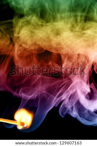 fire lighted match and colored smoke isolated on a black background.
