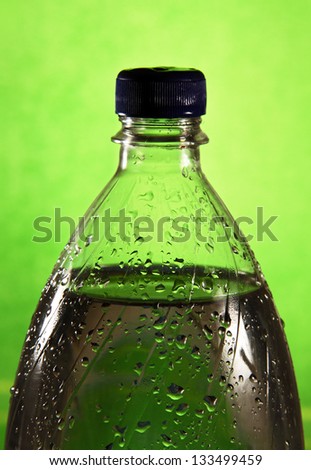 clear plastic bottle filled with water, the picture on a green background.