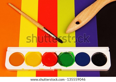 a set of watercolor paints in a plastic case and brush on color background.