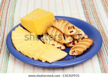 piece of cheese, and thin slices of cheese and a few pastries with filling on a blue plate.
