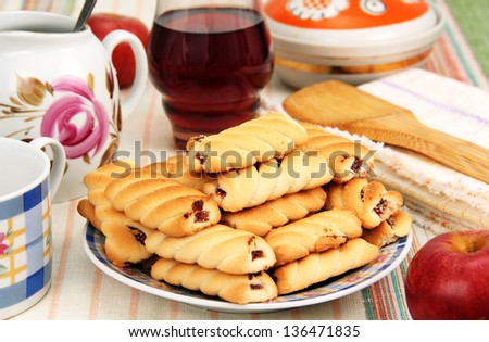 a plate of cookies, a glass with a drink, apple and utensils on the table.