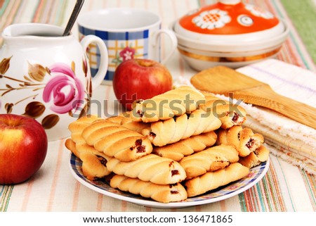 a plate of cookies, two apples and dishes on the dinner table.
