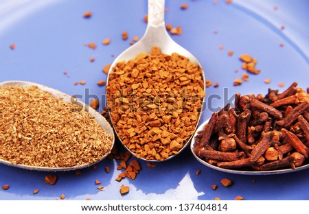 metal spoon of instant coffee and two spoons with spices on a background of blue porcelain plate.