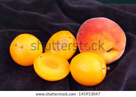 ripe peach and some yellow plums, dark blue velvet background.
