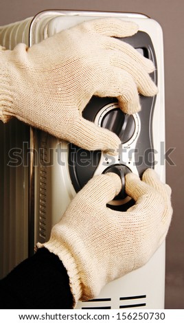 two hands in gloves regulate home oil heater.