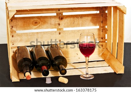 Three empty bottles and glass of rose wine on the background of the wooden box.