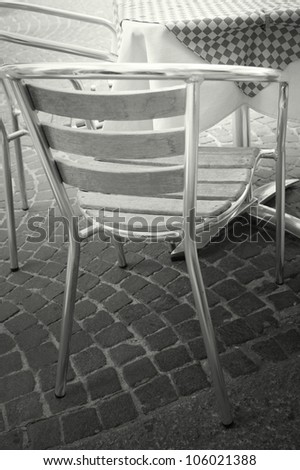Detail of a table with chairs outside of a bar in black and white