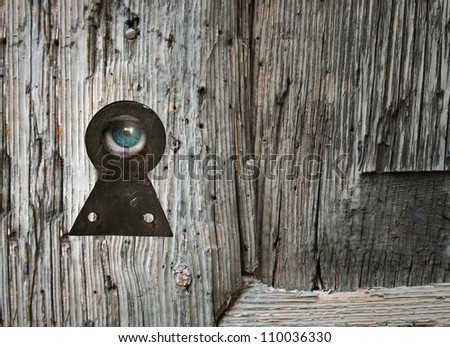 Human eye looking through an old keyhole