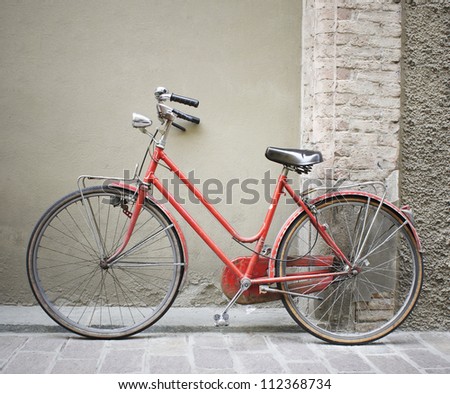 Beautiful old red bicycle leaning on an wall