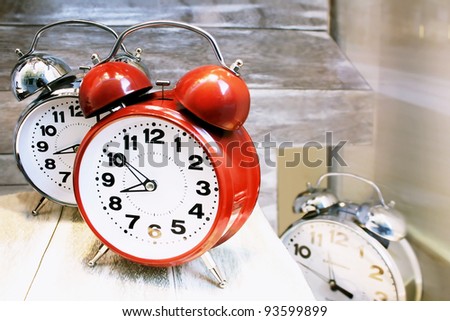 Three round shaped alarm clocks, one red and the other two metallic