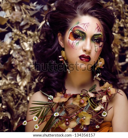 beauty woman with face art and jewelry from flowers orchids