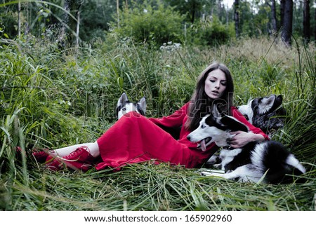 woman in red dress with tree wolfs in forest