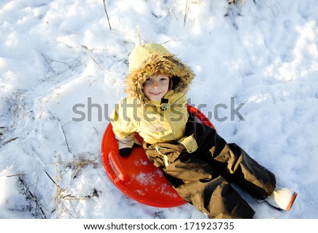 little cute boy in hood with fur on snow outside