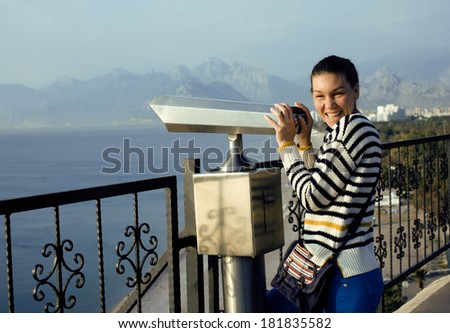 young woman looking through telescope at sea viewpoint in Ataturk park