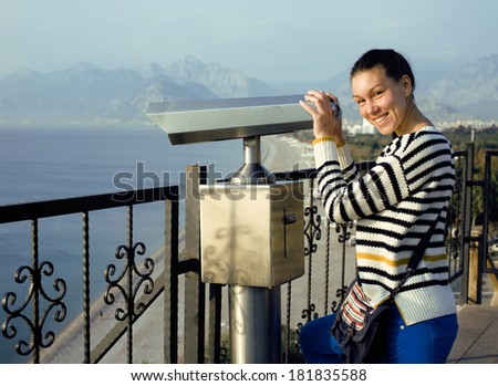 young woman looking through telescope at sea viewpoint in Ataturk park