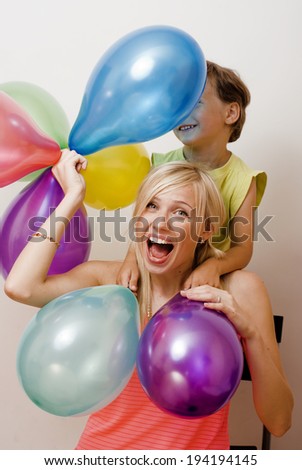 pretty family with color balloons on white background, blond woman with little boy on birthday party