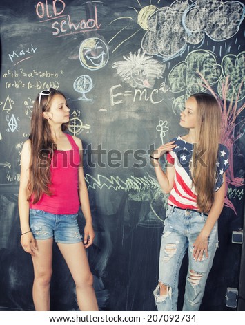 back to school after summer vacations, two teen girls in classroom with blackboard painted