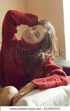 young pretty real woman in sweater and scarf all over her face smiling
