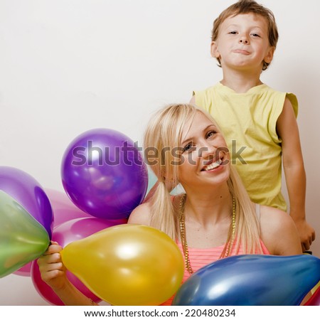 pretty family with color balloons on white background, blond woman with little boy at birthday party
