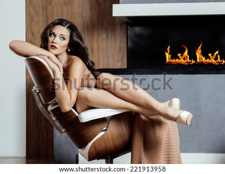beauty yong brunette woman sitting near fireplace at home, winter warm evening in interior