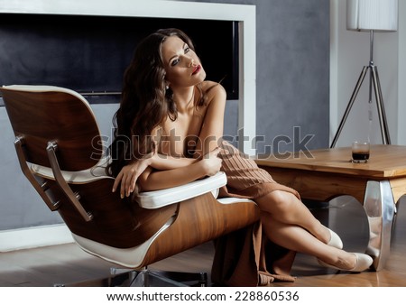 beauty yong brunette woman sitting near fireplace at home, winter warm evening in interior dreaming