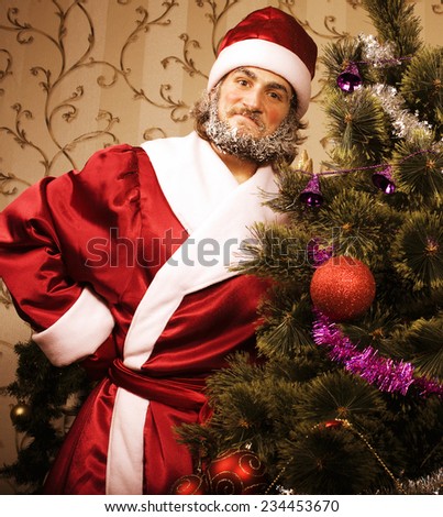 portrait of funny Santa Claus at home with christmass tree, real normal man