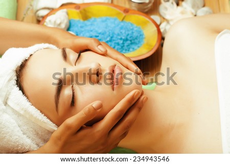 stock photo attractive lady getting spa treatment in salon, close up asian tan hands on face