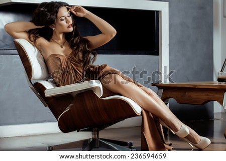 beauty yong brunette woman sitting near fireplace at home, winter warm evening in interior, waiting to celebrate