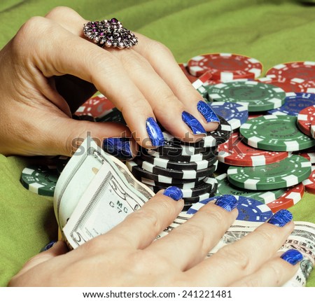 hands of young caucasian woman with blue manicure at casino table close up, deep indigo design on nails