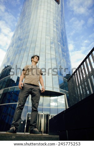 young man stand in front of modern business building, dreams come true