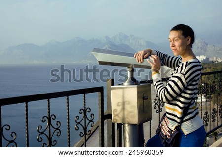 young woman looking through telescope at sea viewpoint in Ataturk park smiling