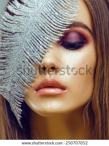 young pretty woman with silver feather like ice decoration to new year, face close up, weathered lips winter