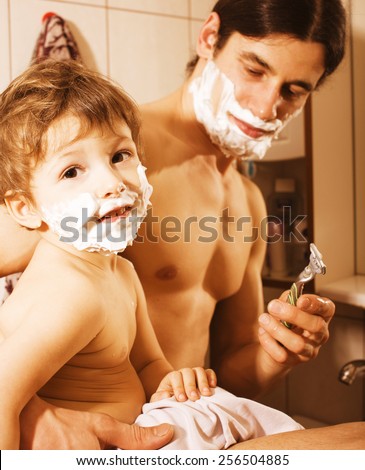 Portrait of son and real  father enjoying while shaving together