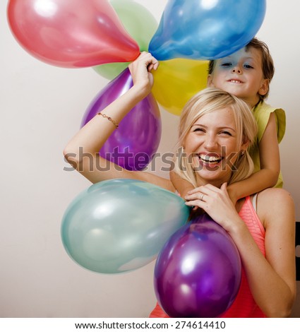 pretty  real family with color balloons on white background, blond woman with little boy at birthday party