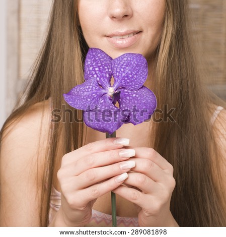 young pretty woman in spa salon with manicure and orchid flower close up smiling no face