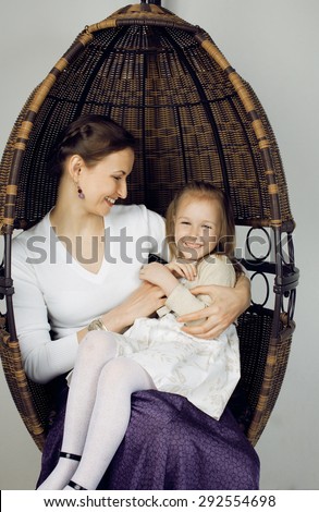 Portrait of mother and daughter at home, happy perfect family in chair smiling