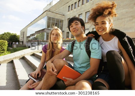 cute group of teenages at the building of university with books huggings, smiling, back to school