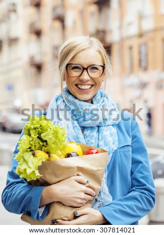 young pretty blond woman with food in bag walking on street healthy cheerful