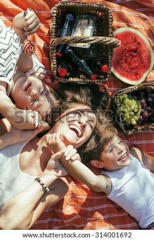 cute happy family on picnic laying on green grass mother and kids, warm summer vacations close up