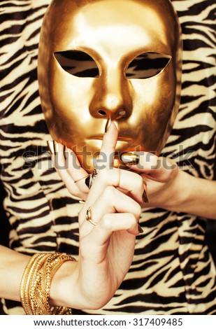 woman hands holding golden carnival mask, rich luxury manicure and jewelry close up on zebra print