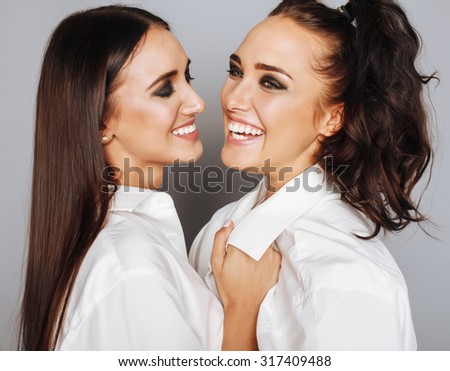 two sisters twins posing, making photo selfie, dressed same white shirt, diverse hairstyle