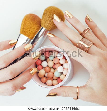 woman hands with golden manicure and many rings holding brushes, makeup artist stuff stylish, pure close up bright