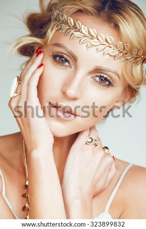 young blond woman dressed like ancient greek godess, gold jewelry close up isolated