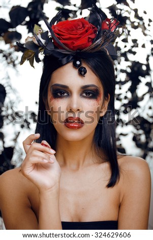 pretty brunette woman with rose jewelry, black and red, bright make up kike a vampire closeup red lips halloween