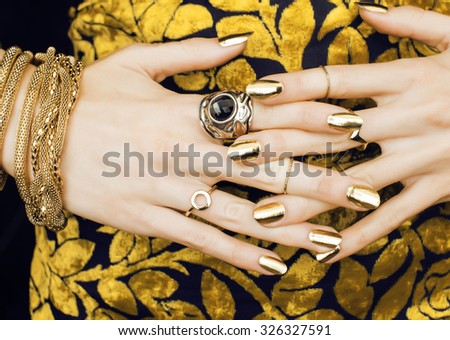 woman hands with golden manicure lot of jewelry on fancy dress close up