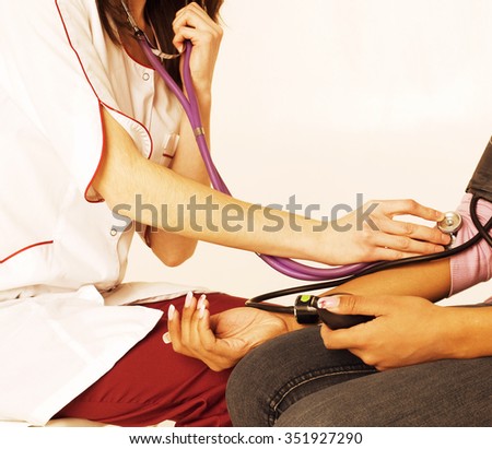 young smiling doctor examine patient, measuring pressure close up, two women in hospital, black and white