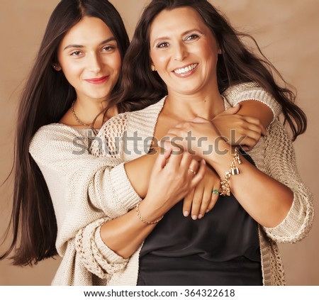 cute pretty teen daughter with mature mother hugging, fashion style brunette makeup close up tann mulattos, warm colors