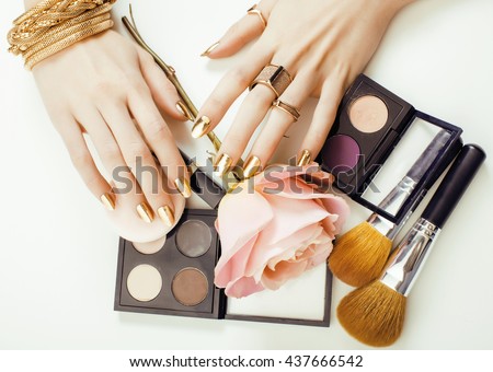 woman hands with golden manicure and many rings holding brushes, makeup artist stuff stylish, pure close up pink
