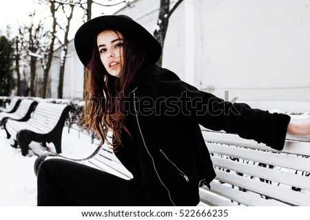 young pretty modern hipster girl waiting on bench at winter snow park alone, lifestyle people concept