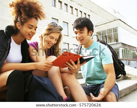 cute group of teenages at the building of university with books huggings, back to school